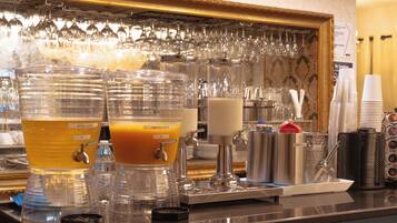 A bar area with multiple beverage dispensers, including apple juice and mango juice, and a variety of glassware.