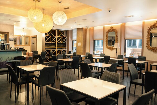 A restaurant with tables and chairs, a counter, and decorative mirrors.