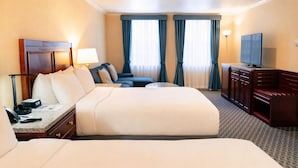 A hotel room with a large bed, a desk with a lamp, a television, and a seating area with a sofa and chairs. - Hotel Stanford (New York)