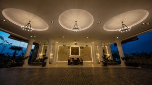 A spacious lobby with a reception desk, seating area, and a large wall with a decorative piece. - Angkor Rendezvous (Siem Reap)