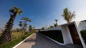 A pathway leading to a modern building with a white exterior and a brown door. - Angkor Rendezvous (Siem Reap)