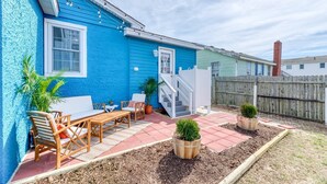 Une maison bleue avec un patio, des meubles en bois et des plantes en pot.