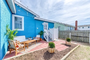 A blue house with a patio, wooden furniture, and potted plants. - Close to Beach, Modern! Trendy! (Kill Devil Hills)