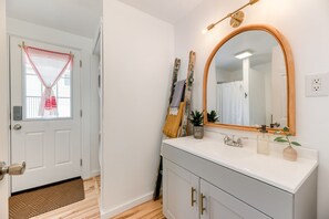 Een badkamer met een wit wastafelmeubel, een grote spiegel en een douchegordijn.