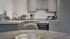 Una cocina moderna con armarios grises, un microondas, un hervidor y una cafetera.