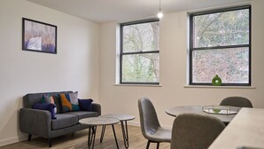 Una sala de estar moderna con un sofá gris, dos mesas redondas y una mesa de comedor con sillas.