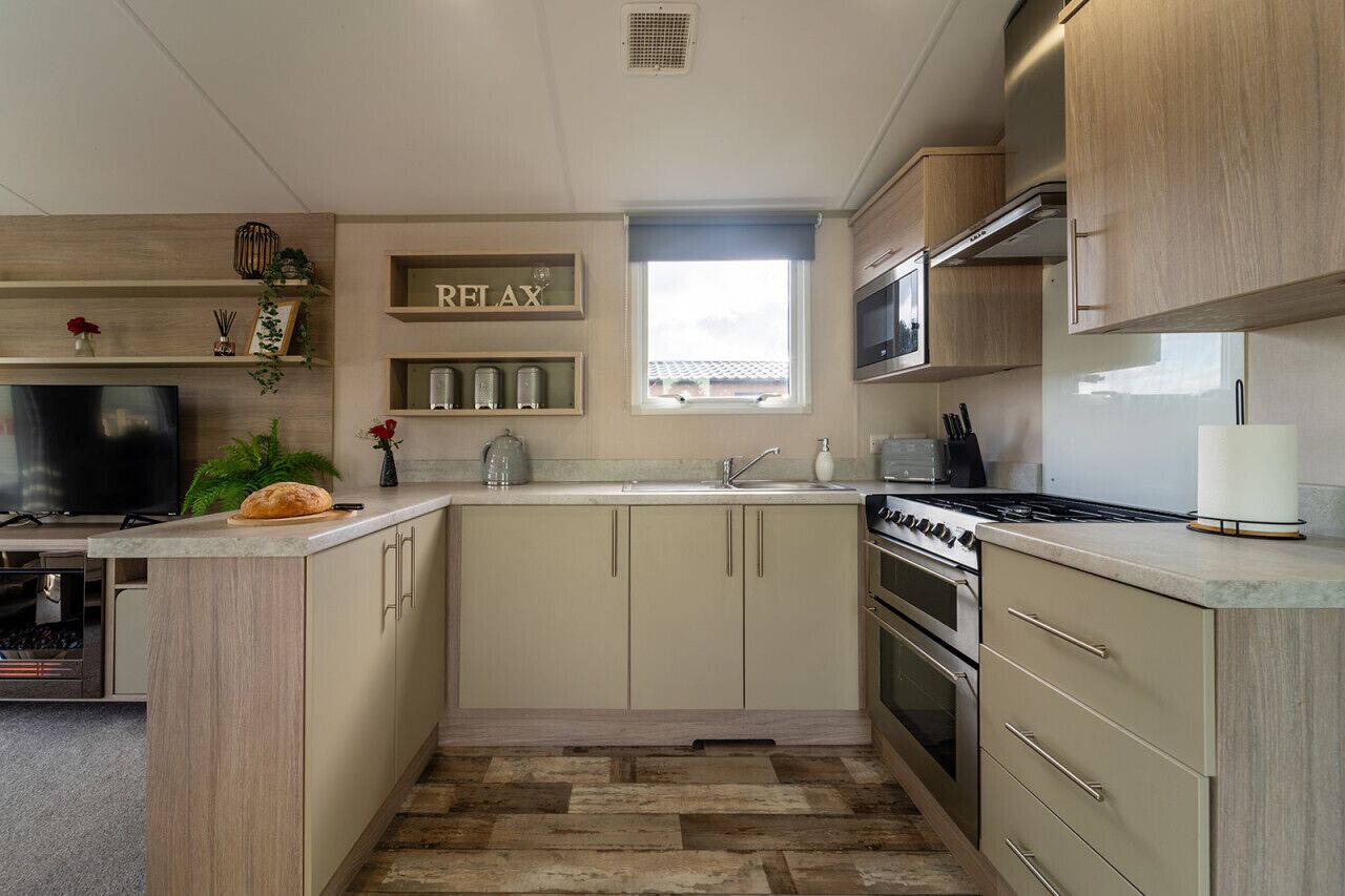 Una cocina moderna con armarios de madera, horno empotrado, microondas y un ventanal amplio.