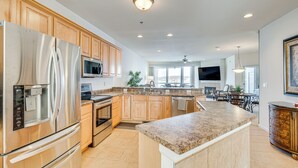 A modern kitchen with stainless steel appliances, wooden cabinets, and a granite countertop. - Lakeside Osage Beach Condo in Lands End Community (Osage Beach)