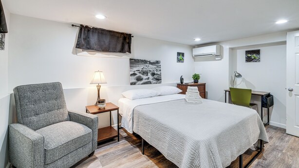 Een slaapkamer met een bed, een stoel, een bureau en een nachtkastje.
