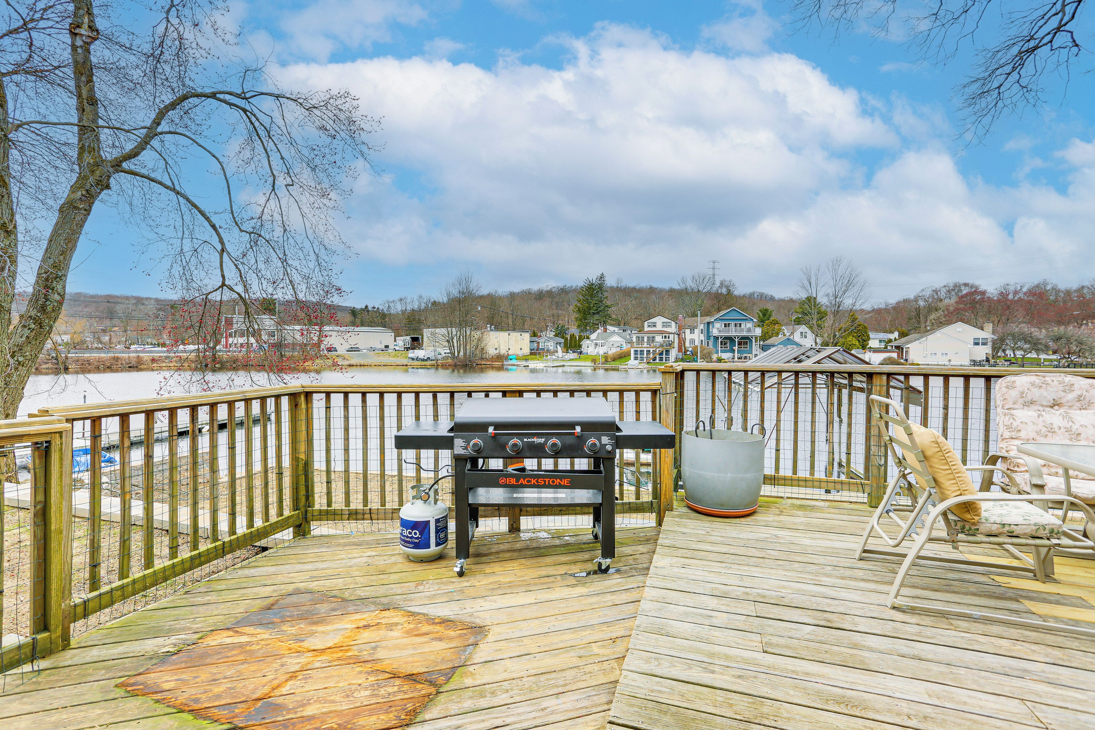 A wooden deck with a grill, a chair, and a gas canister.
