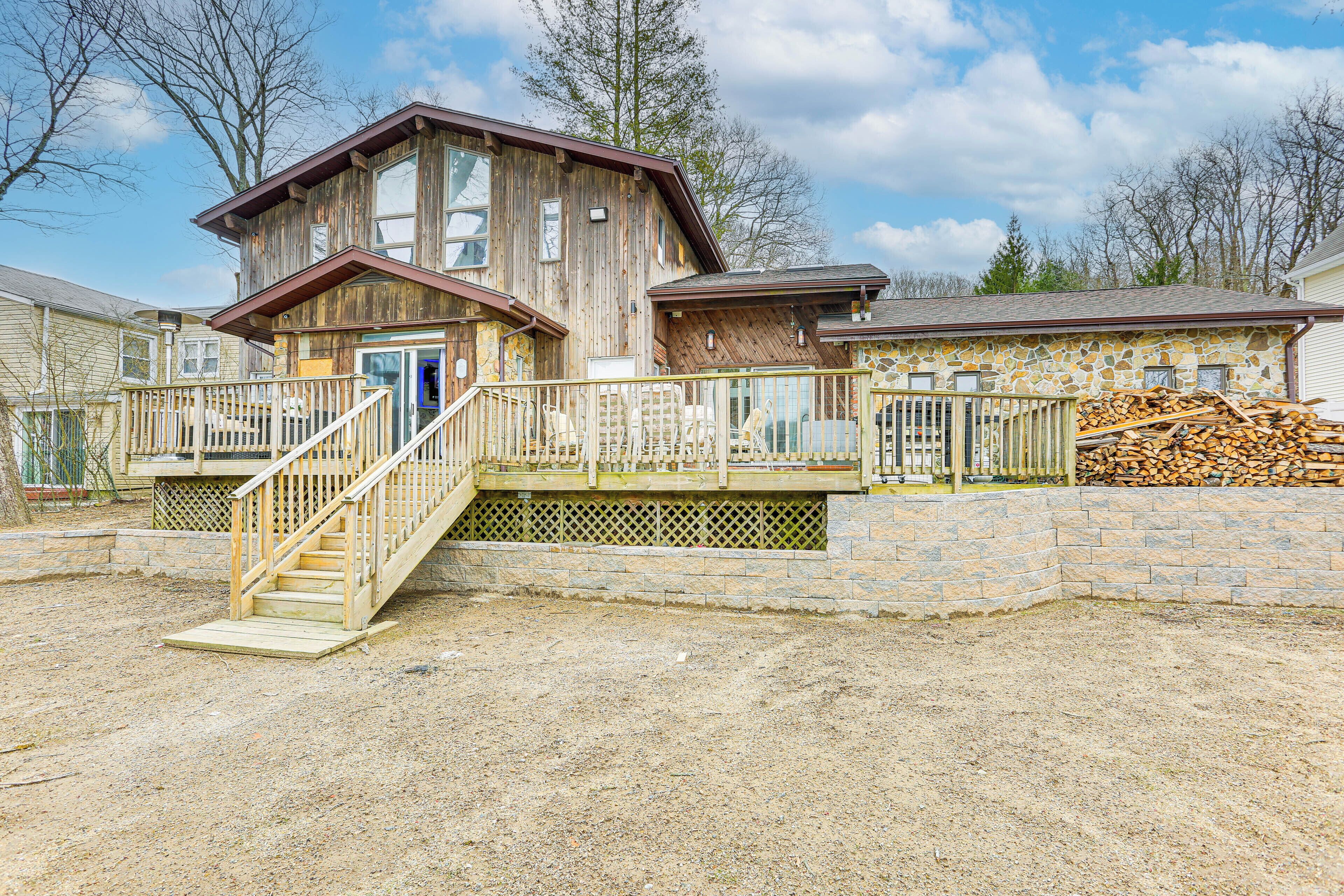 A wooden house with a stone foundation, a wooden deck, and a staircase leading to the entrance.