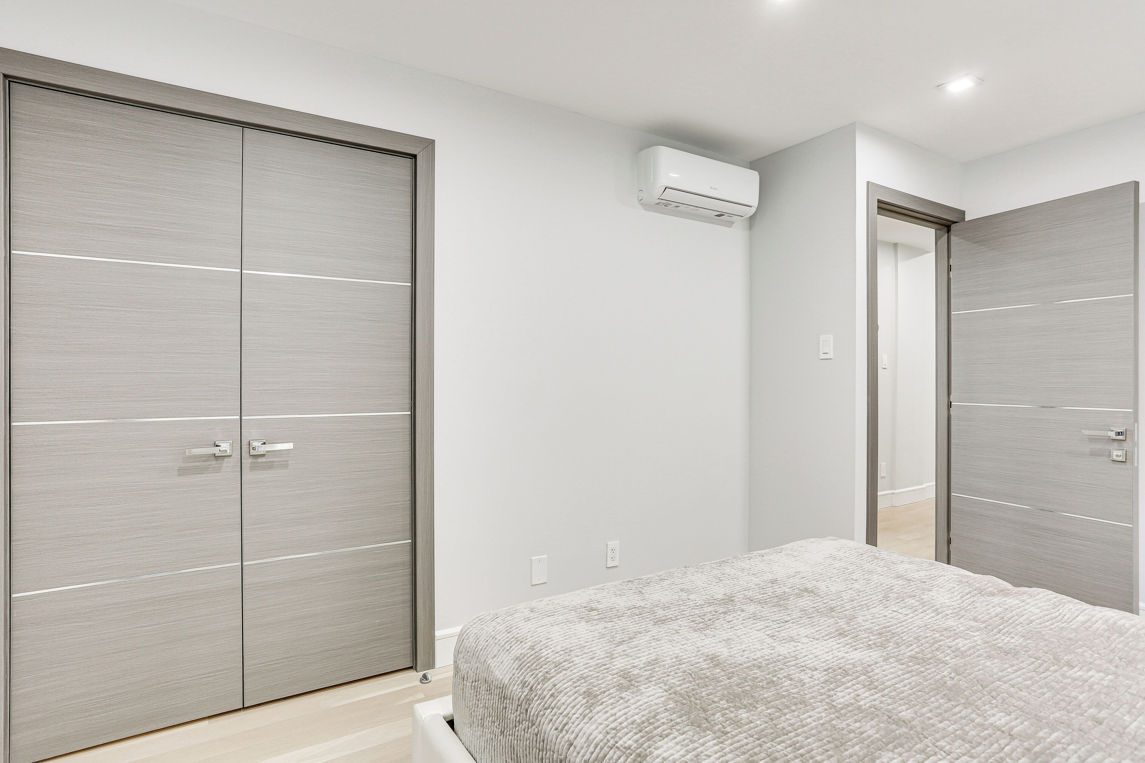 A bedroom with a bed, a wardrobe, and an air conditioning unit.