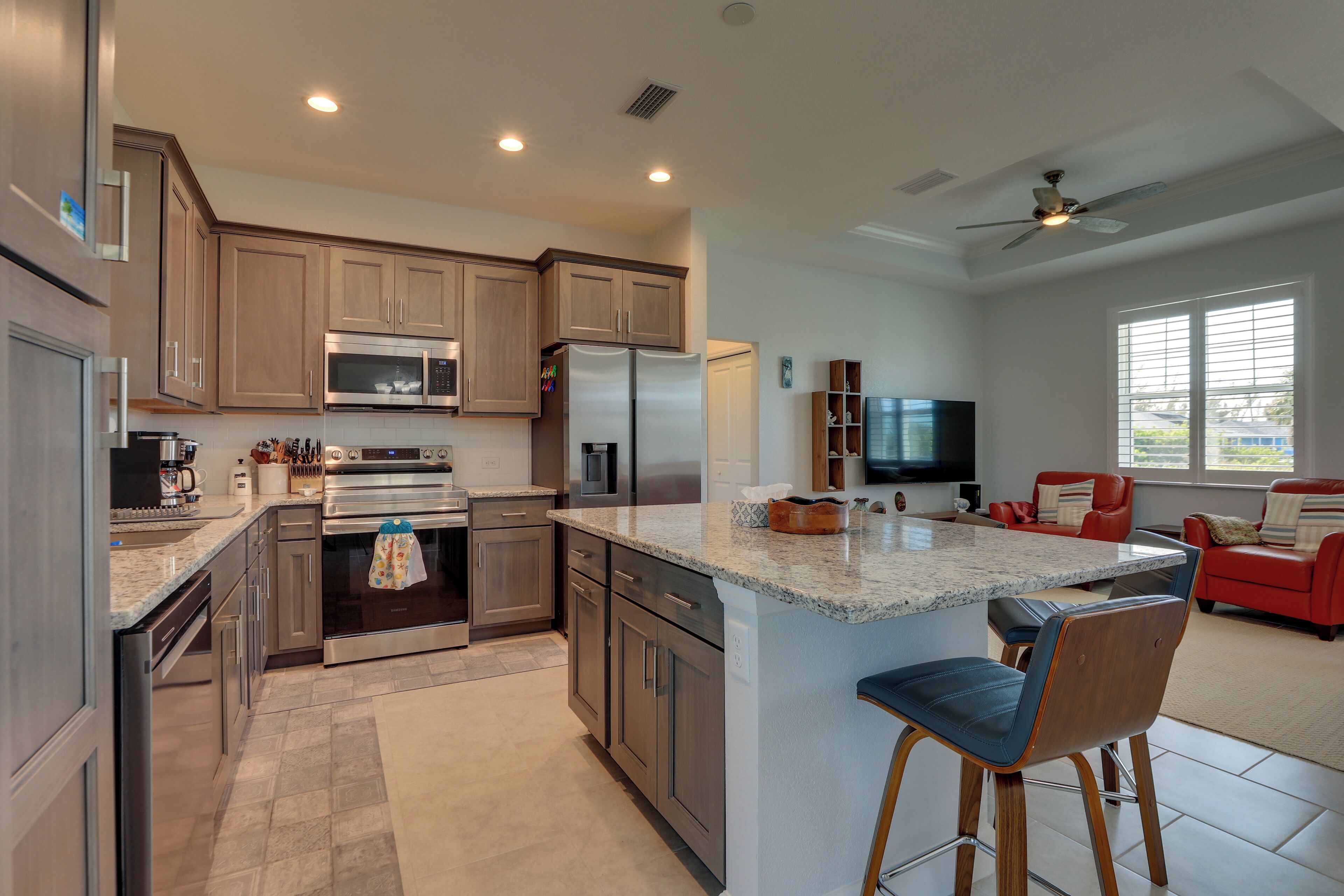 A modern kitchen with stainless steel appliances, wooden cabinets, and a large island with bar stools.