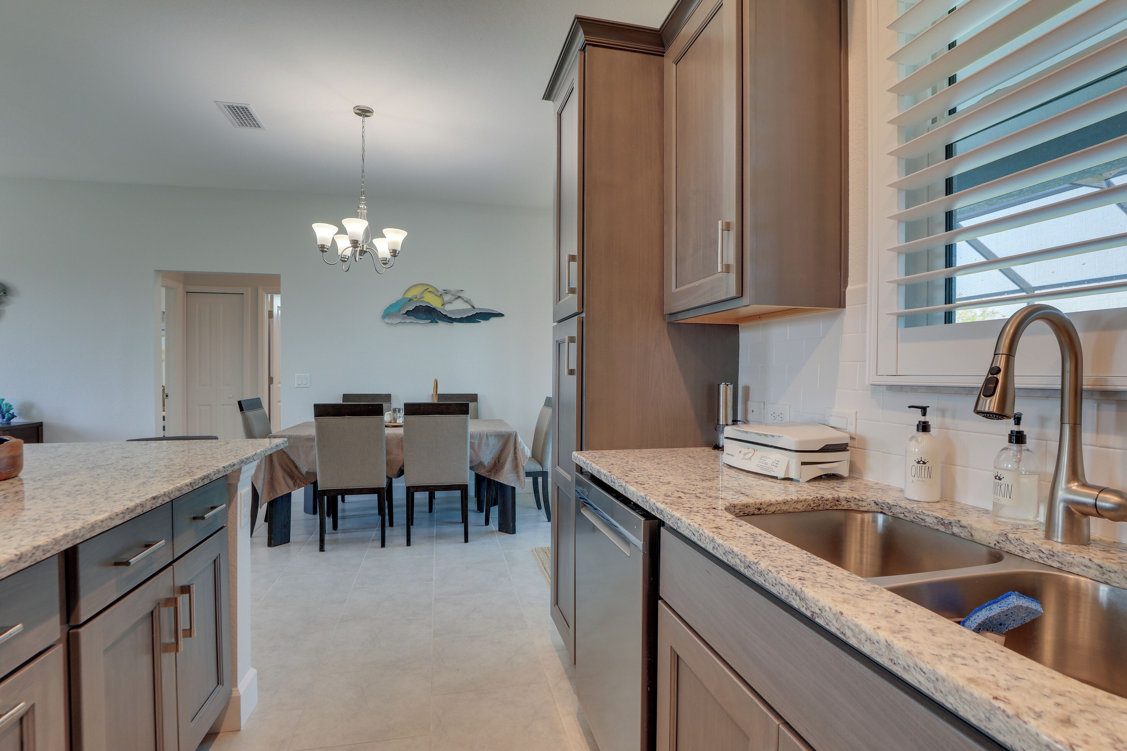 A modern kitchen with granite countertops, stainless steel appliances, and a dining area with a table and chairs.