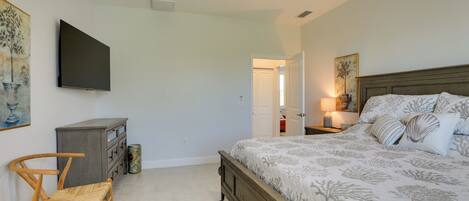 A bedroom with a bed, a desk, a chair, a ceiling fan, and artwork on the walls.