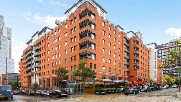 Un hôtel à plusieurs étages, avec une façade en briques rouges, des balcons et un restaurant situé au rez-de-chaussée.