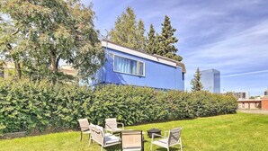 Une maison mobile bleue dotée d’un jardin aménagé avec des meubles d’extérieur et une haie.