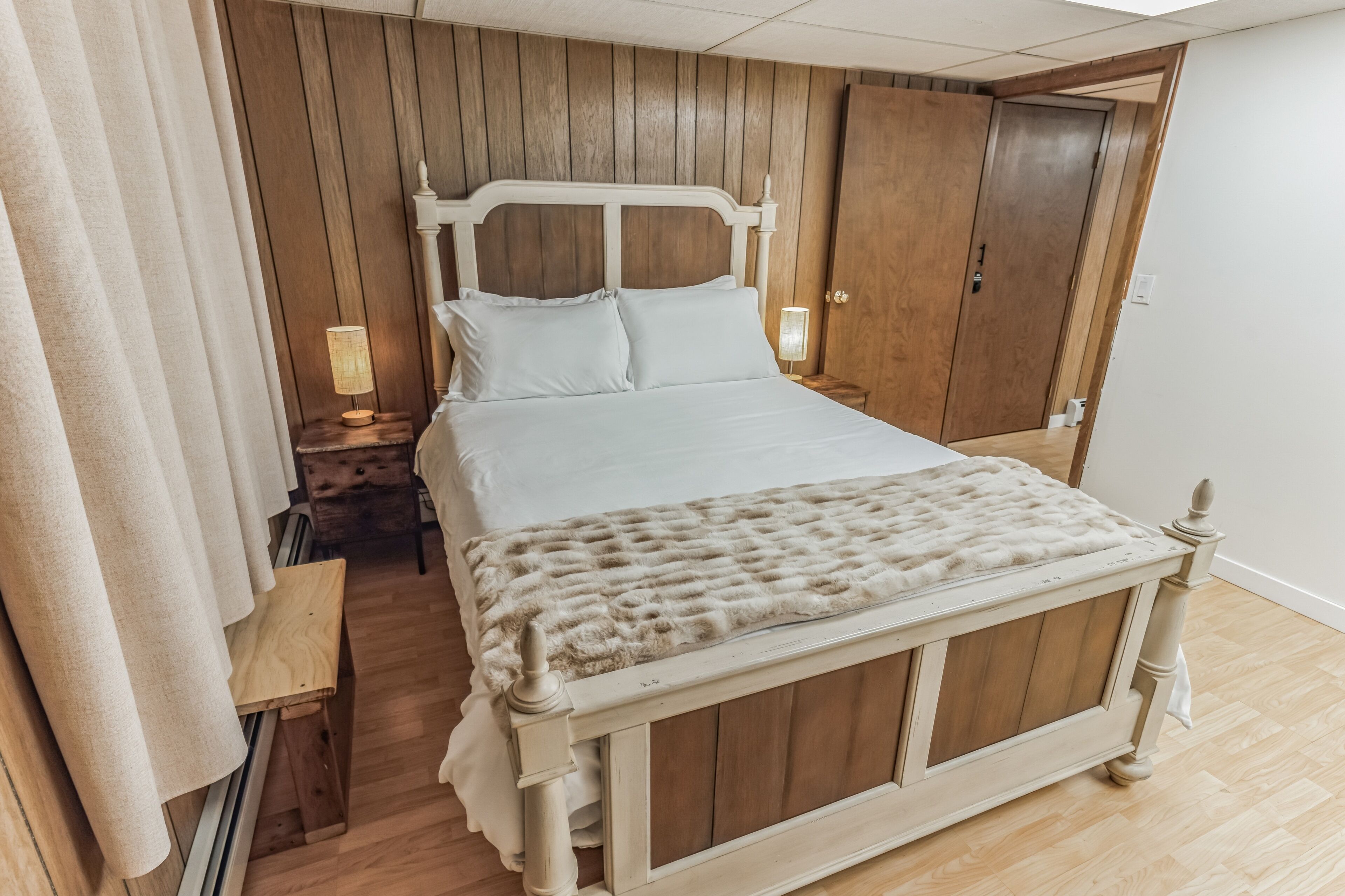 A bedroom with a wooden bed frame, a bedside table with a lamp, and a wardrobe.