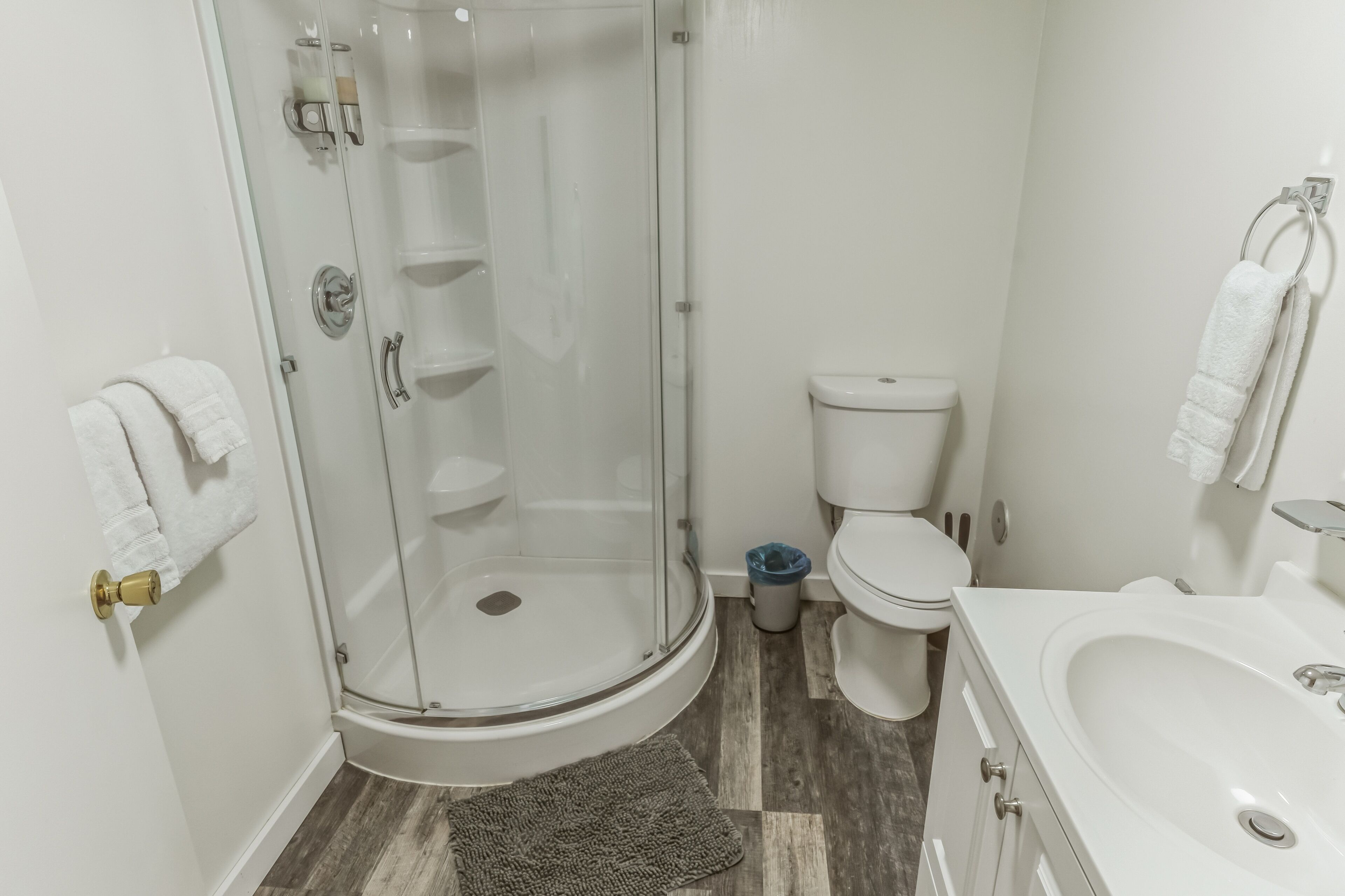 A bathroom with a glass-enclosed shower, a toilet, and a sink.