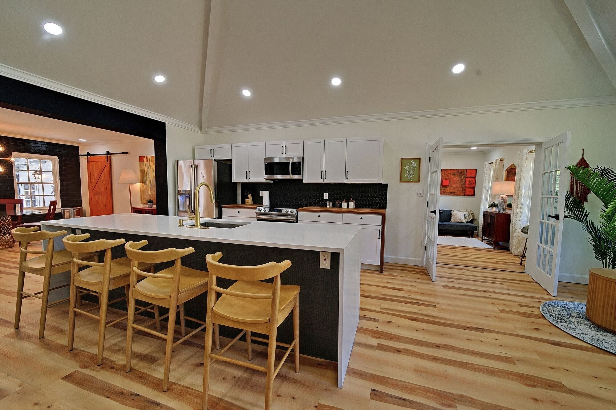 Una cocina amplia con una isla grande, sillas de madera y electrodomésticos modernos.