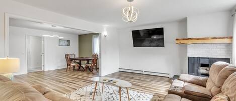 Uma sala de estar moderna com piso de madeira, sofás bege, uma mesa de centro e uma lareira.