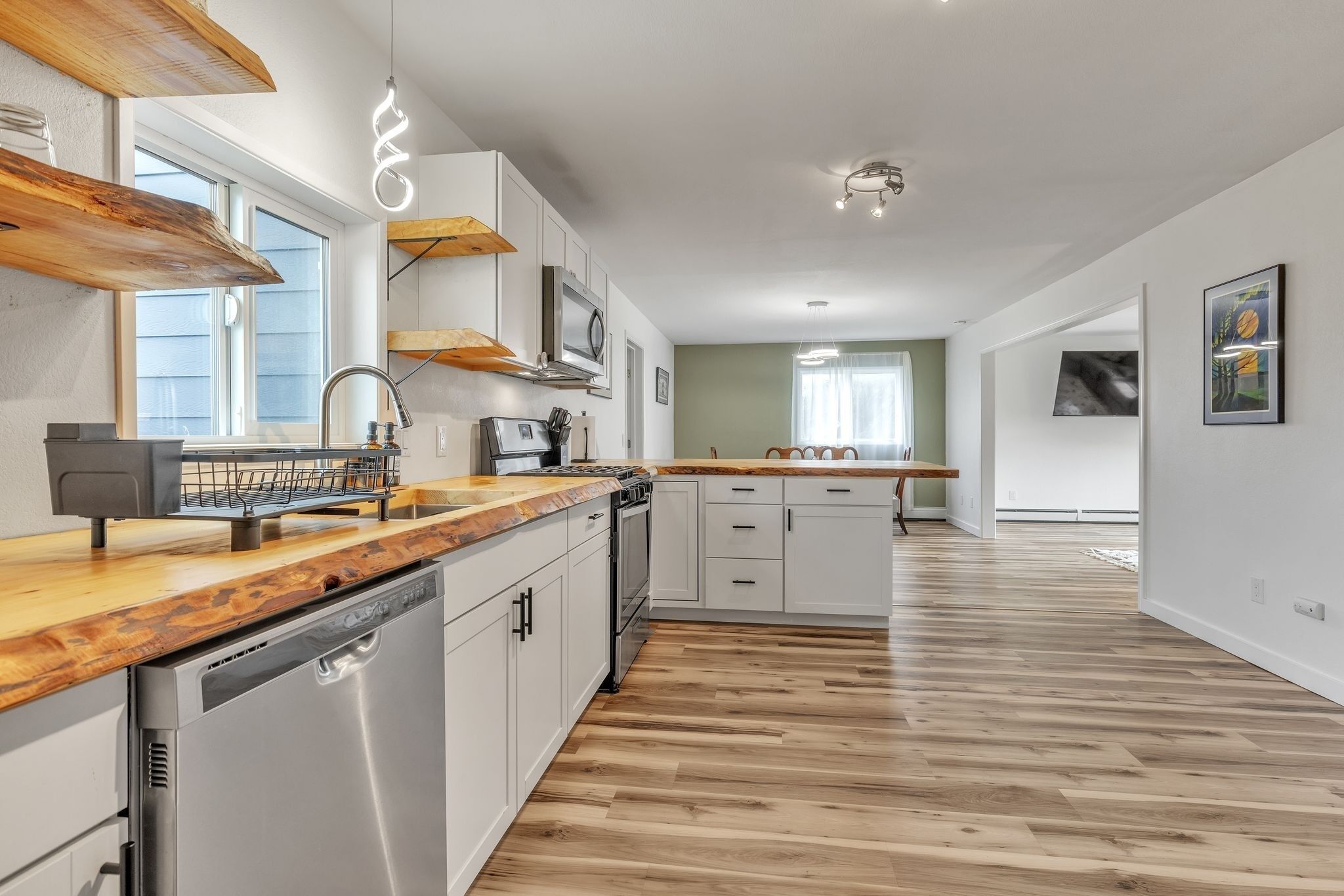 Une cuisine moderne avec des plans de travail en bois, des appareils électroménagers en acier inoxydable et un îlot central.