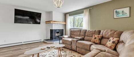 A modern living room with a sectional sofa, a fireplace, and a large window.