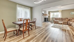 Uma sala de estar ampla com uma mesa de jantar de madeira e cadeiras, um sofá e uma lareira.