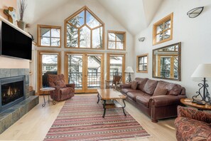 A spacious living room with a fireplace, large windows, and a cozy seating area.