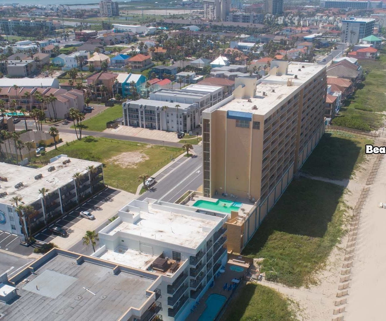 An aerial view of a coastal urban area with a hotel named 'Surfsidel' and a beach access point.