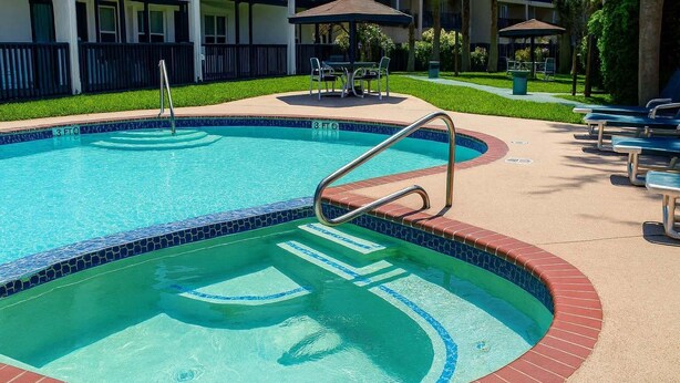 A swimming pool with a tiled edge, a metal ladder, and lounge chairs around the pool area. - Surfside Ii #109 2 Bedroom Home by RedAwning (South Padre Island)