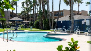 A swimming pool with lounge chairs and palm trees. - Surfside Ii #109 2 Bedroom Home by RedAwning (South Padre Island)