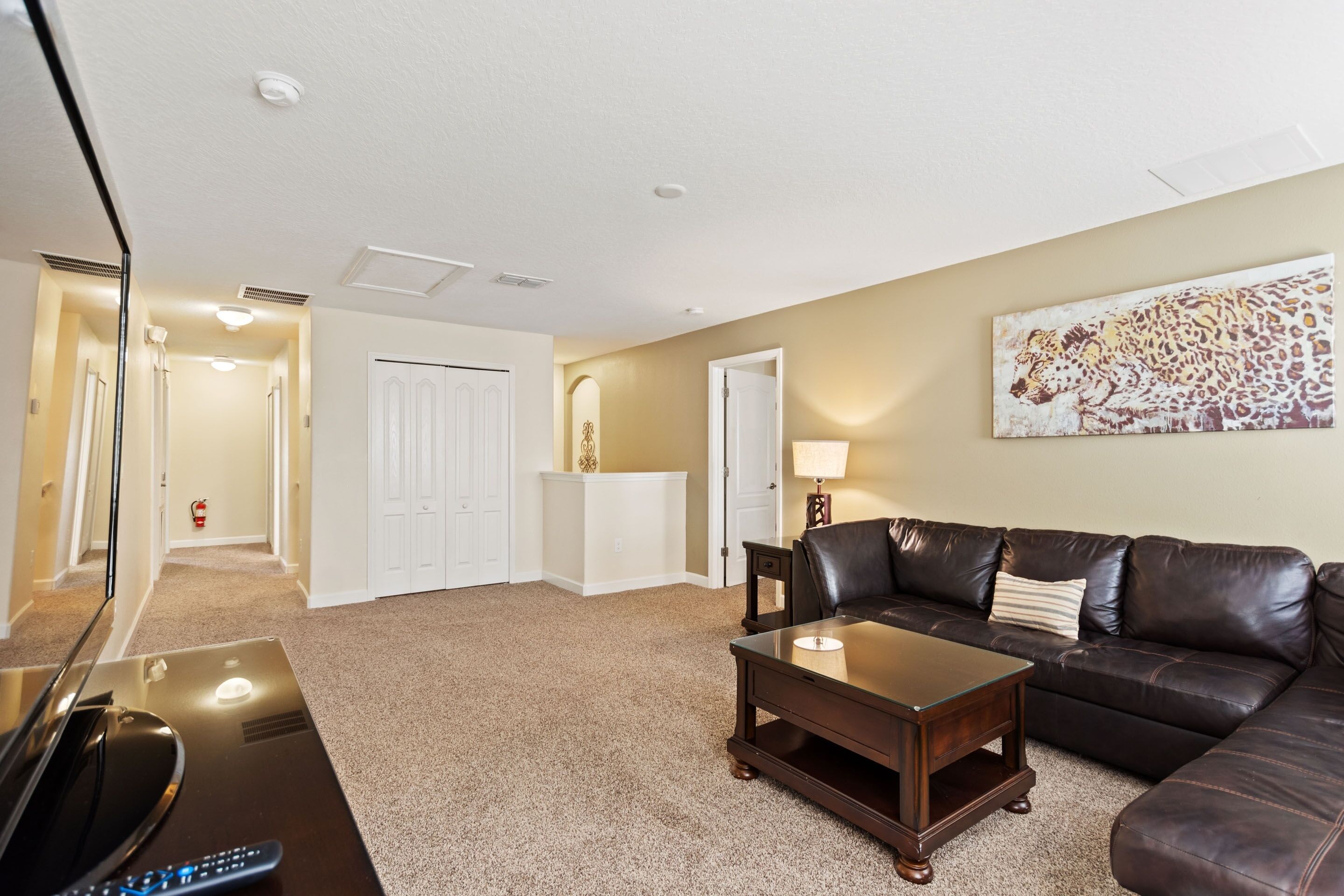 A living room with a brown leather couch, a wooden coffee table, and a beige carpet.