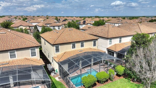 Zona residencial con varias casas de tejados de cerámica y una piscina central rodeada de vegetación.