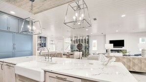 A spacious kitchen with a large island, modern pendant lights, and a built-in TV. - Best of the Best! Gulf Front with Heated Pool, Private Gym, Private Elevator (Panama City Beach)