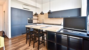 A modern kitchen with a central island, dark cabinetry, and a flat-screen TV. - Modern apartment with 2 bedrooms near Arena (Pula)