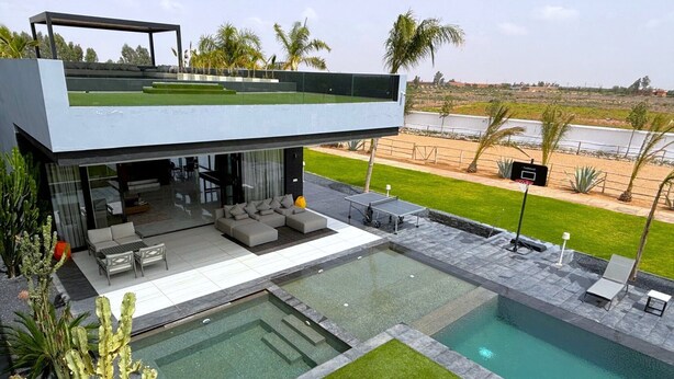 Une maison moderne dotée d’une piscine, d’un espace extérieur aménagé et offrant une vue sur le paysage environnant.