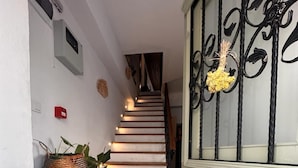 Una escalera con baldosas estampadas en el suelo que conduce a un rellano con un felpudo que dice 'Welcome'.