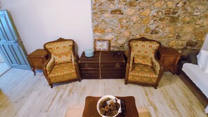 Un salón con dos sillones estampados, una mesita con un cuenco de piñas y una pared de piedra.