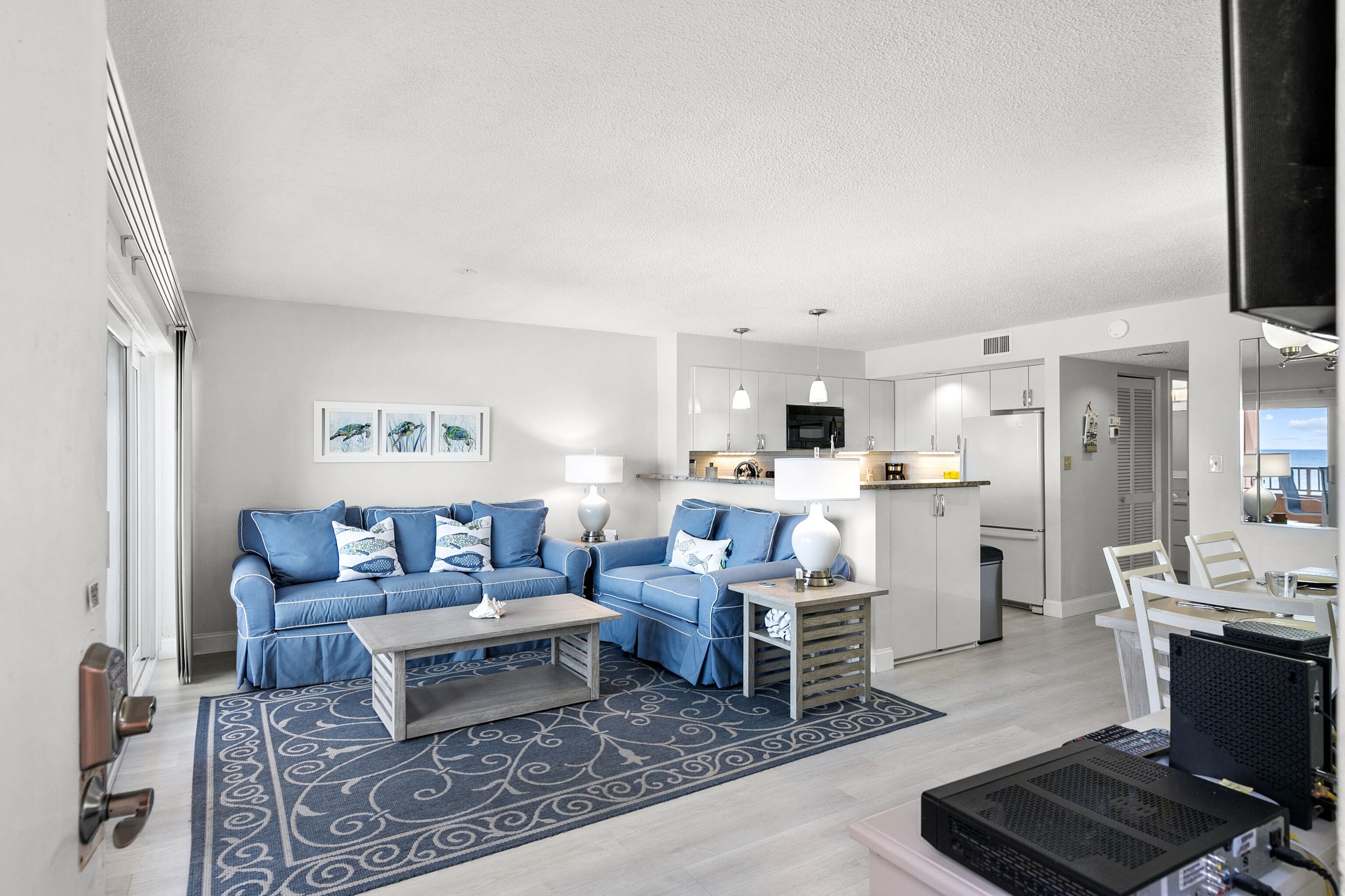 A modern living room with a blue sofa set, a coffee table, and a patterned rug.