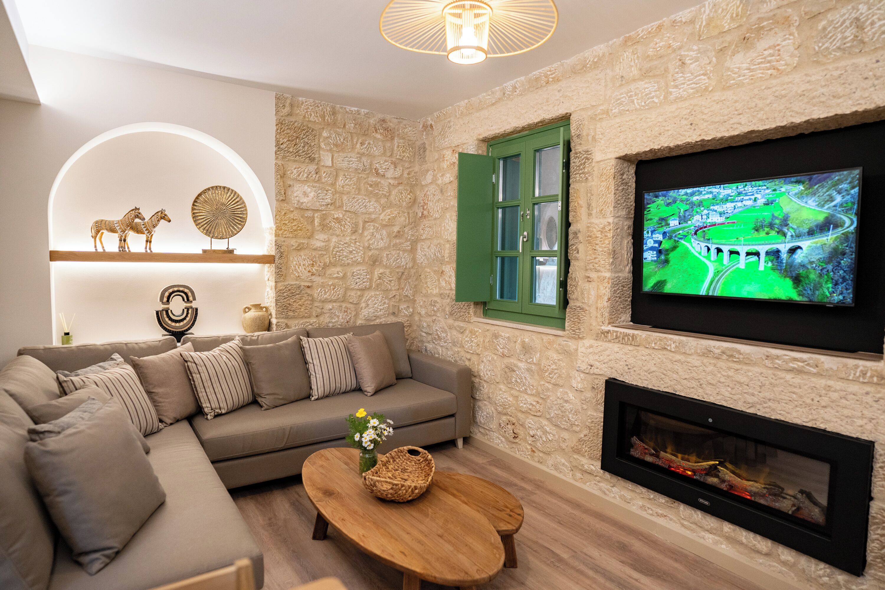 A living room with a stone wall, a green door, a fireplace, a television, and a sofa.