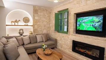 A living room with a stone wall, a green door, a fireplace, a television, and a sofa.
