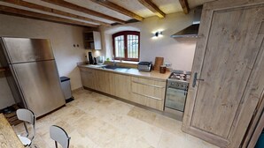 Una cocina con armarios de madera, un refrigerador de acero inoxidable, una estufa a gas y una ventana con vistas.