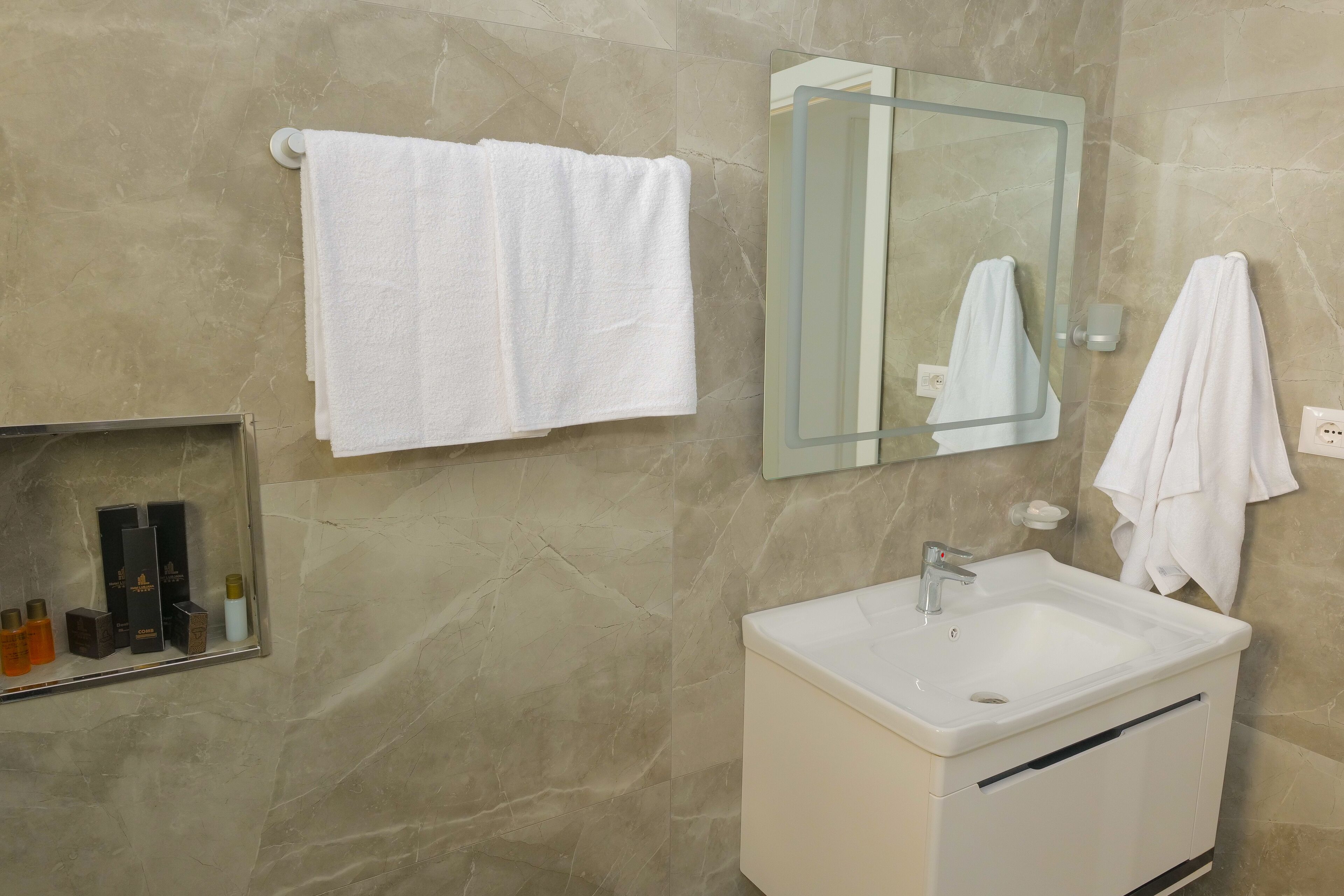 A bathroom with a white sink, a mirror, and a towel rack.