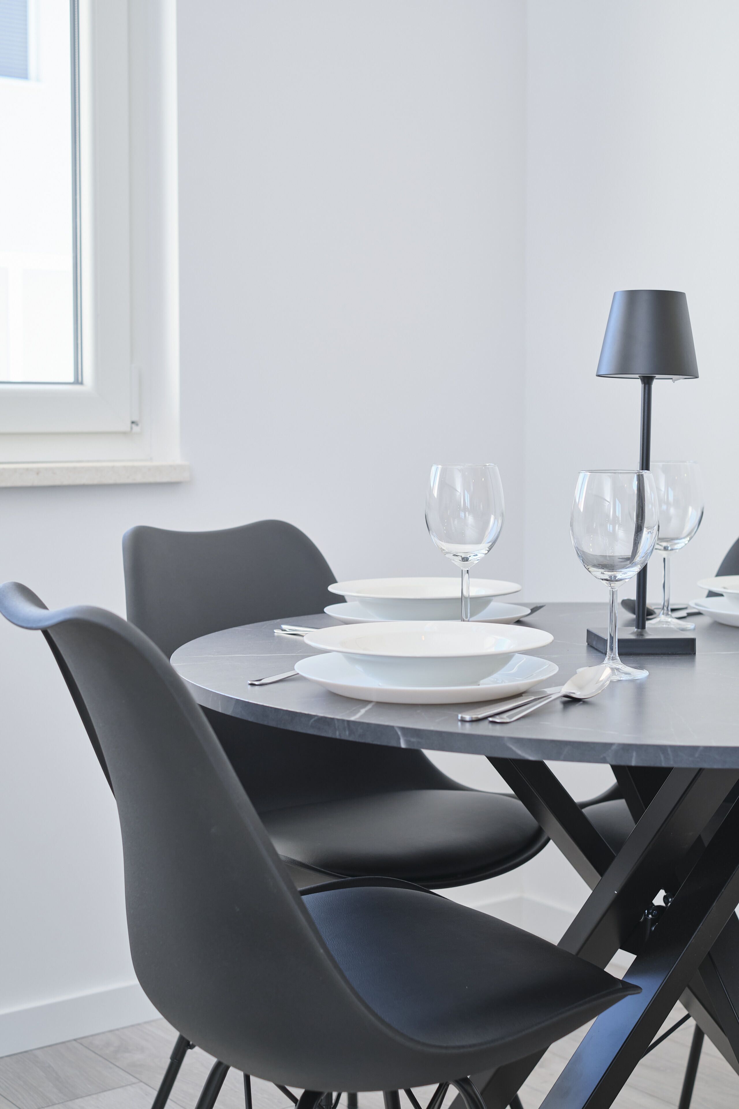 Un comedor moderno con una mesa redonda, sillas negras y una lámpara de pie.