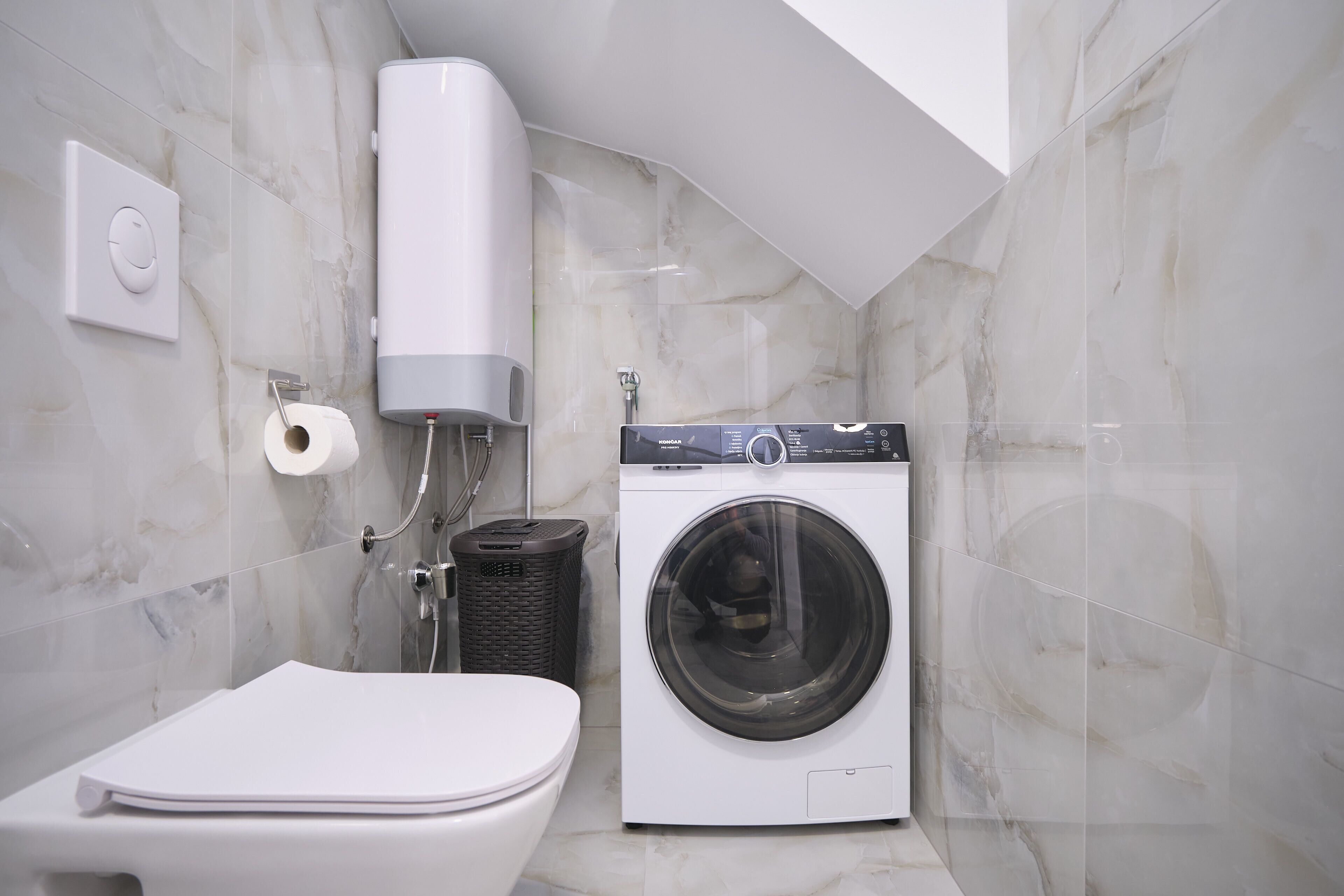 Un bagno compatto con il water, una lavatrice e un erogatore di asciugamani.