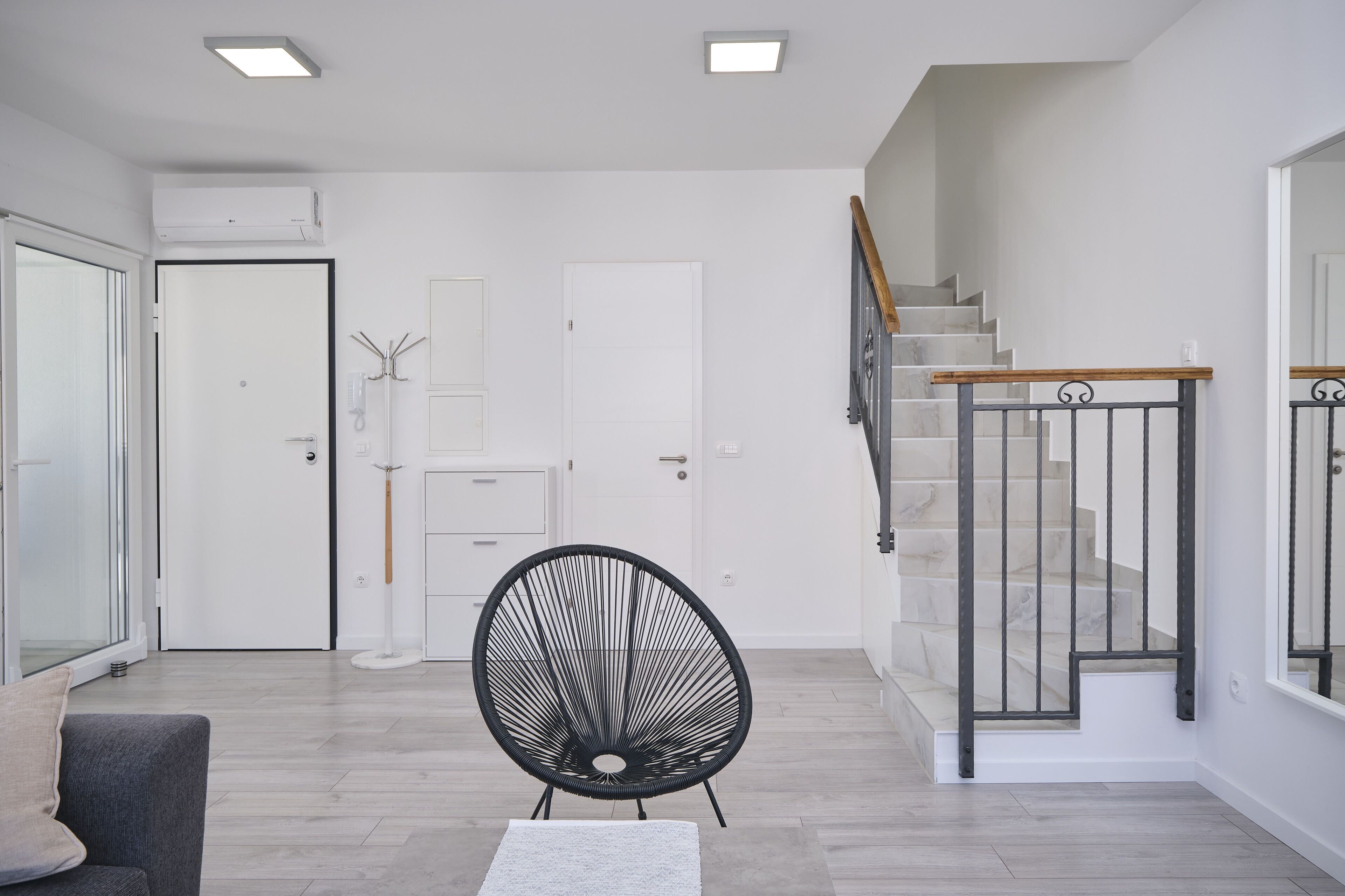 A modern living room with a staircase, a black chair, and a white sofa.