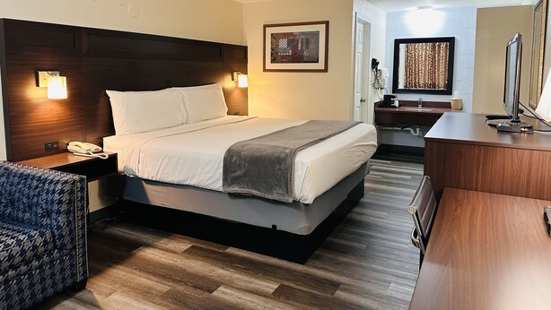 Een hotelkamer met een groot bed, bedlampen, een bureau, een stoel en een spiegel.