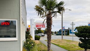 Een motel met een bord, een palmboom en een voetpad.