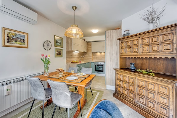 A modern kitchen with wooden cabinets, a dining table with chairs, and a pendant light. - West Oasis With Terrace (Zagreb)